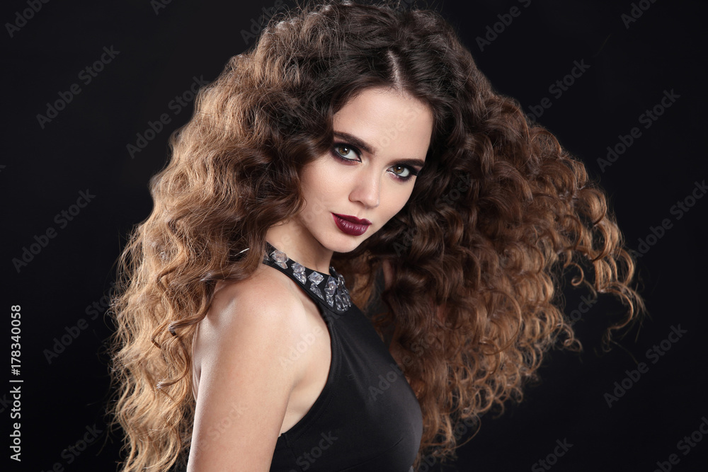 Beauty girl hair. Curly hairstyle. brunette girl with healthy long hair, beauty makeup. Beautiful woman with marsala matte lips, blowing hairstyle isolated on black background Beauty girl hair. Curly hairstyle. brunette girl with healthy long hair, beauty makeup. Beautiful woman with marsala matte lips, blowing hairstyle isolated on black background