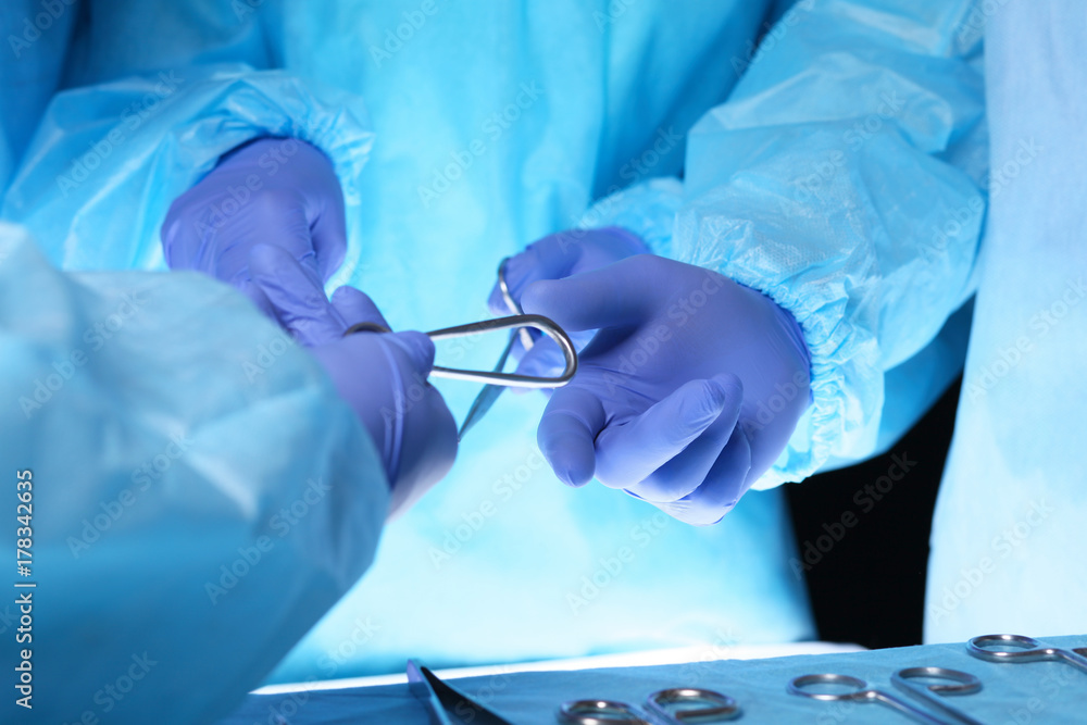 Surgeons hands holding surgical scissors and passing surgical equipment, close-up. Health care and veterinary concept Surgeons hands holding surgical scissors and passing surgical equipment, close-up. Health care and veterinary concept