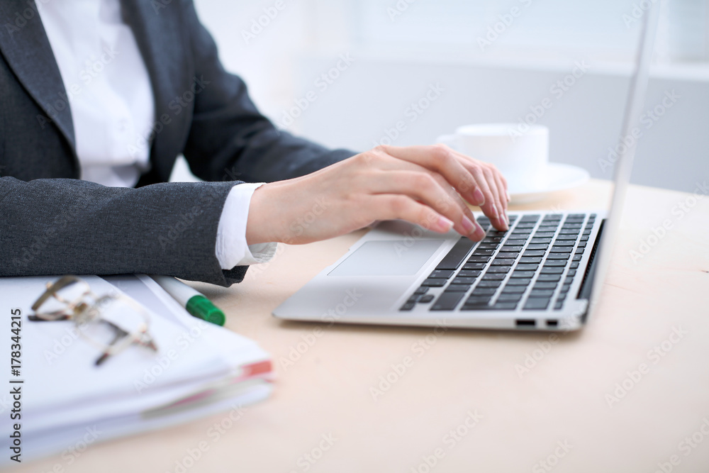 Close-up of business woman hands typing on laptop computer in the white colored office. Close-up of business woman hands typing on laptop computer in the white colored office.