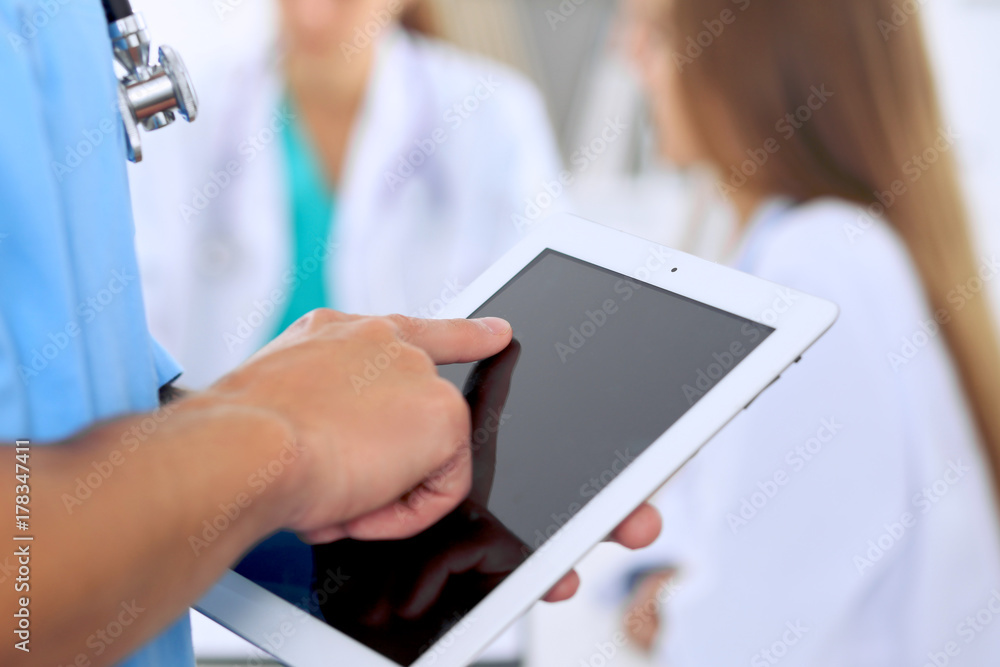 Surgeon doctor using tablet computer, close-up of hands at touch pad screen Surgeon doctor using tablet computer, close-up of hands at touch pad screen