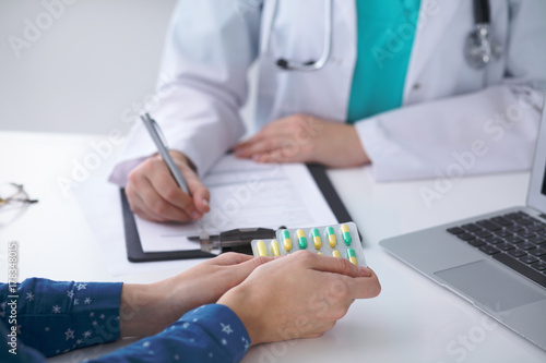  Close-up of a doctor and  patient  sitting at the desk while physician pointing into laptop computer. Medicine and health care concept