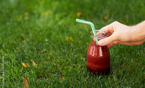 Healthy red detox drink in hand. Fresh beet smoothie jar outdoors. Diet or healthy lifestyle, well being and weight loss concept