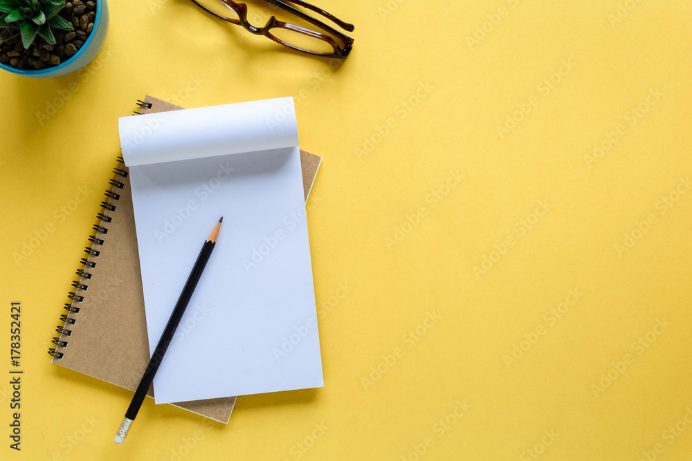 notebook and pencil on yellow desk - obrazy, fototapety, plakaty 