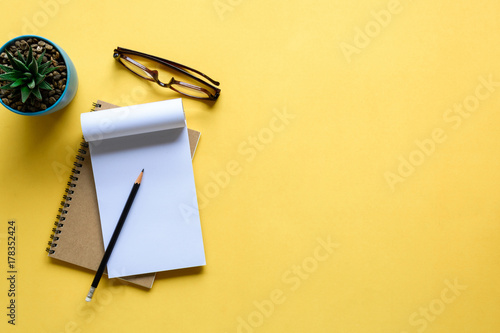 notebook and pencil on yellow desk