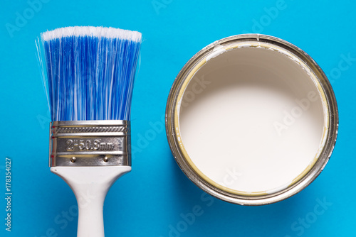 Brush and paint can on blue background