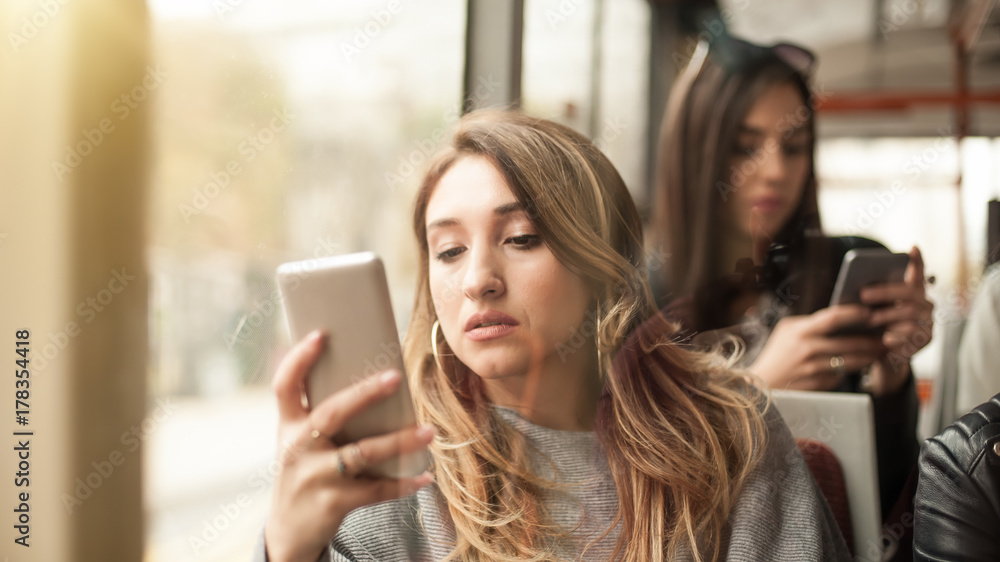 Young girl uses a mobile phone in the city bus