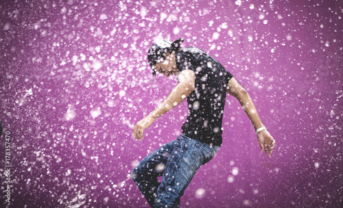 Young man standing in shower of water drops