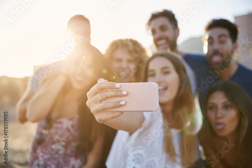 Blurred portrait of group of friends making faces to selfie