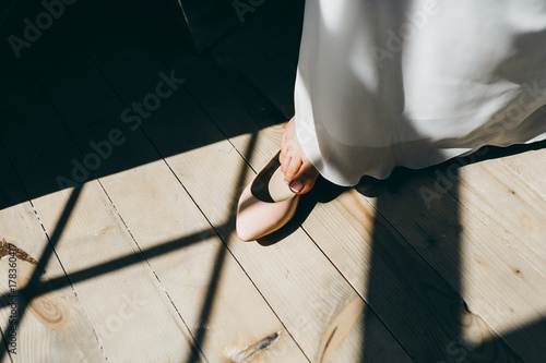 Bride is putting her leg in wedding shoes. Artwork.