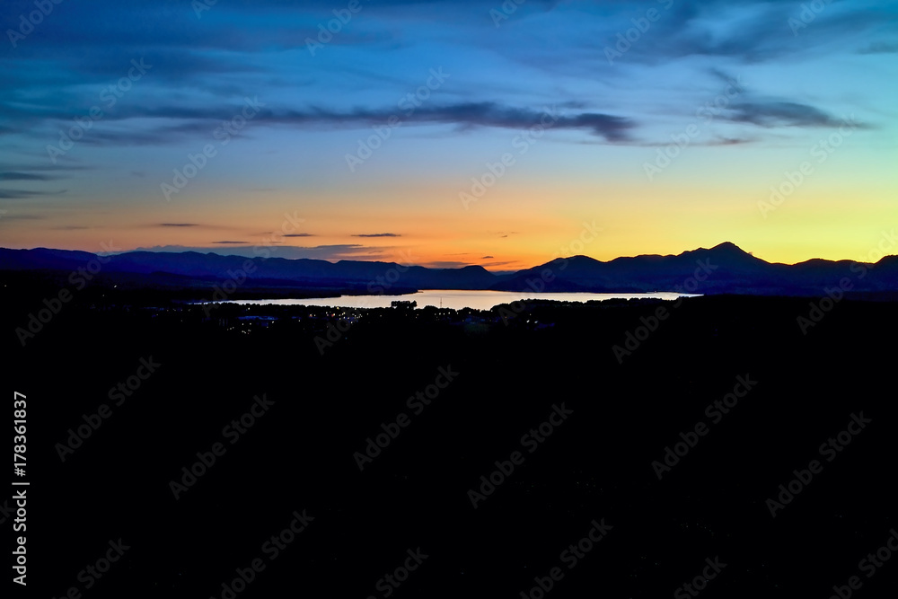 Obraz premium City lights with a background of the magic color sky above the Liptovsk Mara dam at sunset.