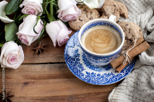 coffee in a vintage cup  on a wooden background and a bouquet of white roses