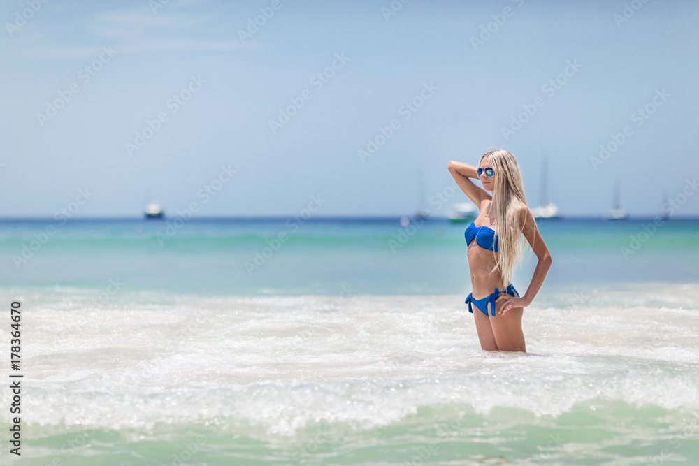 blond woman in blue bikini on white tropic beach