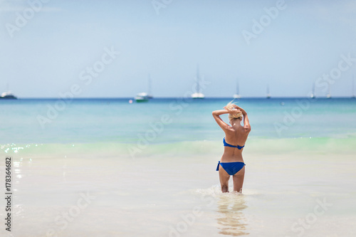 blond woman in blue bikini on white tropic beach
