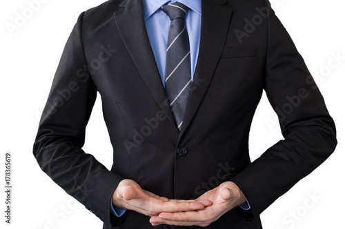 Mid section of businessman in suit while standing with hands