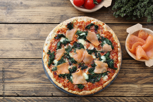 pizza con pesce salmone affumicato e spinaci su sfondo rustico photo