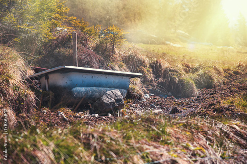 Fototapeta Naklejka Na Ścianę i Meble -  Old bath tub resting on rocks in a meadow in the hills of Germany at sunrise.