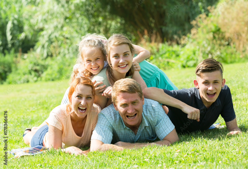 the large family lying on the grass in park.