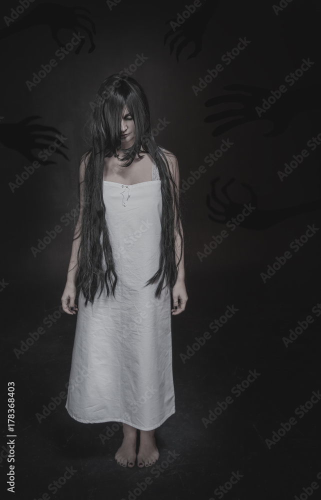 Mystical ghost woman with long black hair and shadow hands on dark