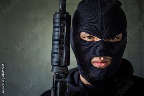 Terrorist or gunman wearing a mask and holding a gun ready to fire