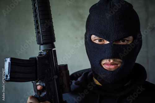 Terrorist or gunman wearing a mask and holding a gun ready to fire