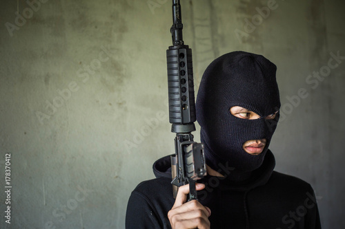 Terrorist or gunman wearing a mask and holding a gun ready to fire