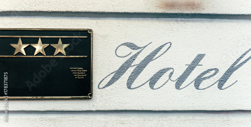 Beautiful HOTEL calligraphy sign next to three stars metallic plate next to entrance door