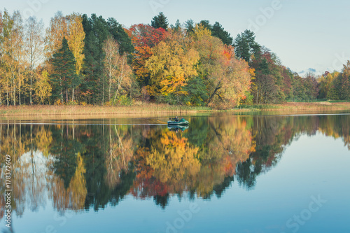 Farewell to Autumn as the final leaf-fall has begun. Sunny October day at   rai  i lake with stunning mirror reflections in water. 