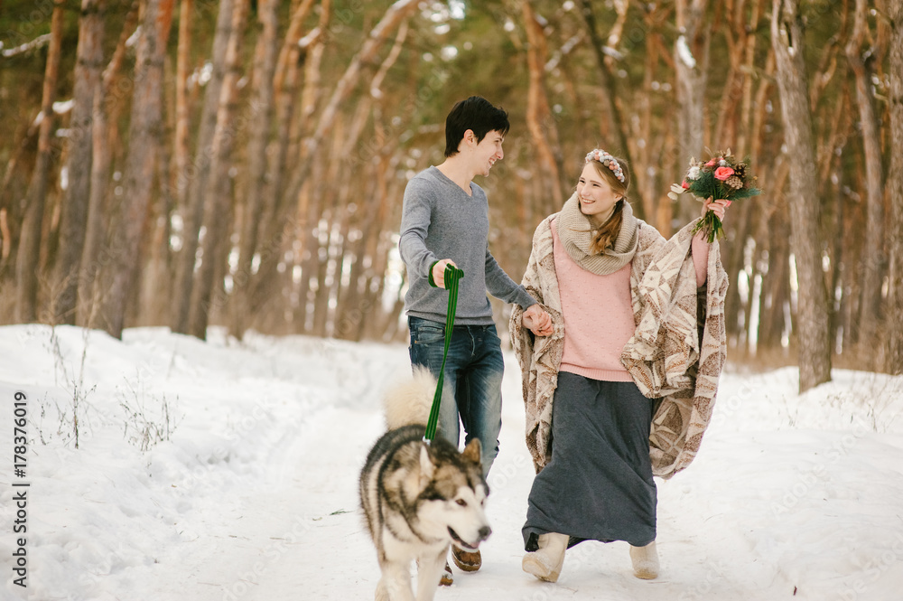 Outdoor happy couple in love posing with dog in cold winter weather. Young boy and girl having fun outdoor. Boho