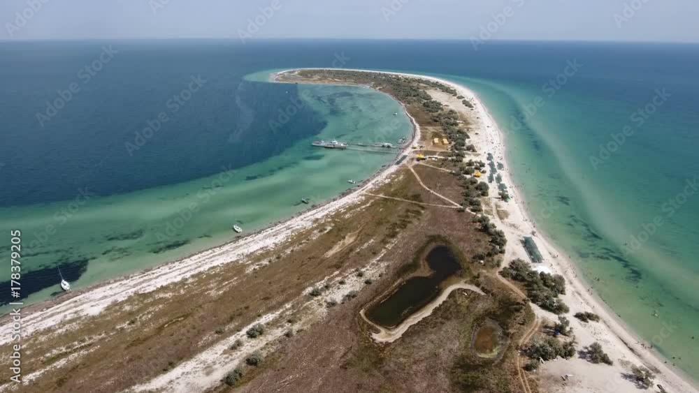 An inspiring bird`s eye view of a curvy and long spit of Dzharylhach island in the Black Sea in summer. It is covered with multicolored weeds and wetland. The seascape looks beautiful and fine An inspiring bird`s eye view of a curvy and long spit of Dzharylhach island in the Black Sea in summer. It is covered with multicolored weeds and wetland. The seascape looks beautiful and fine