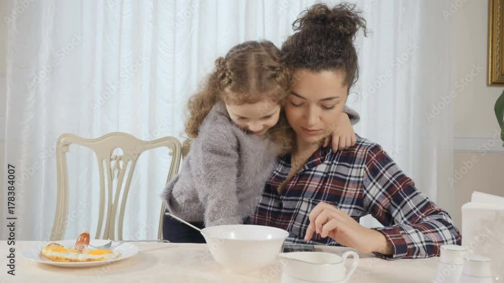 Woman and girl embrace each other during breakfast Woman and girl embrace each other during breakfast