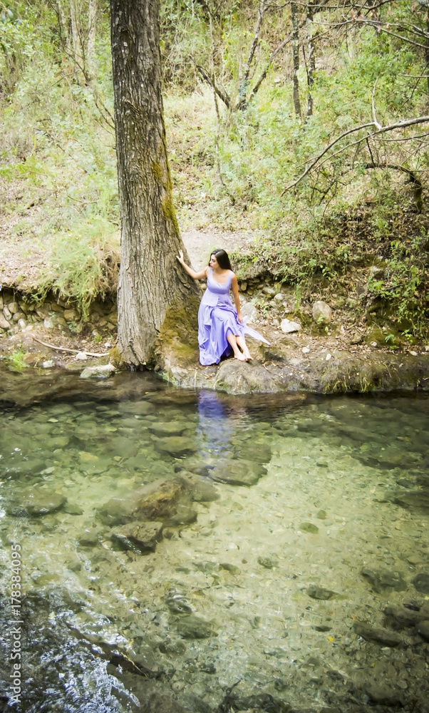 Beautiful woman on the bank of a mountain river with an evening dress