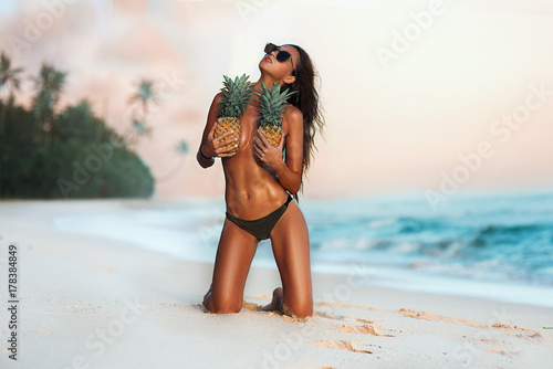  sexy beautiful girl on the beach with pineapples and palm trees with an attractive figure and belly press