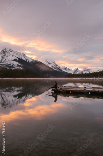 Woman Hiker Sitting on a Mountain Lake Dock at Sunrise on a Cold Morning