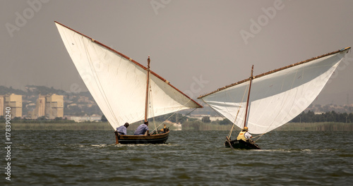 two traditional wooden boats sailing in a regatta. Latin sailing ships in the Albufera in Valencia Spain