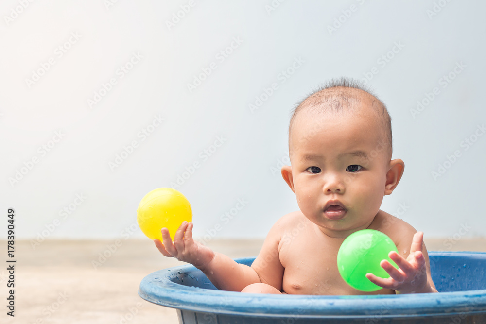 Cute New Born Baby playing ball in the plastic basin during shower,children learning Cute New Born Baby playing ball in the plastic basin during shower,children learning