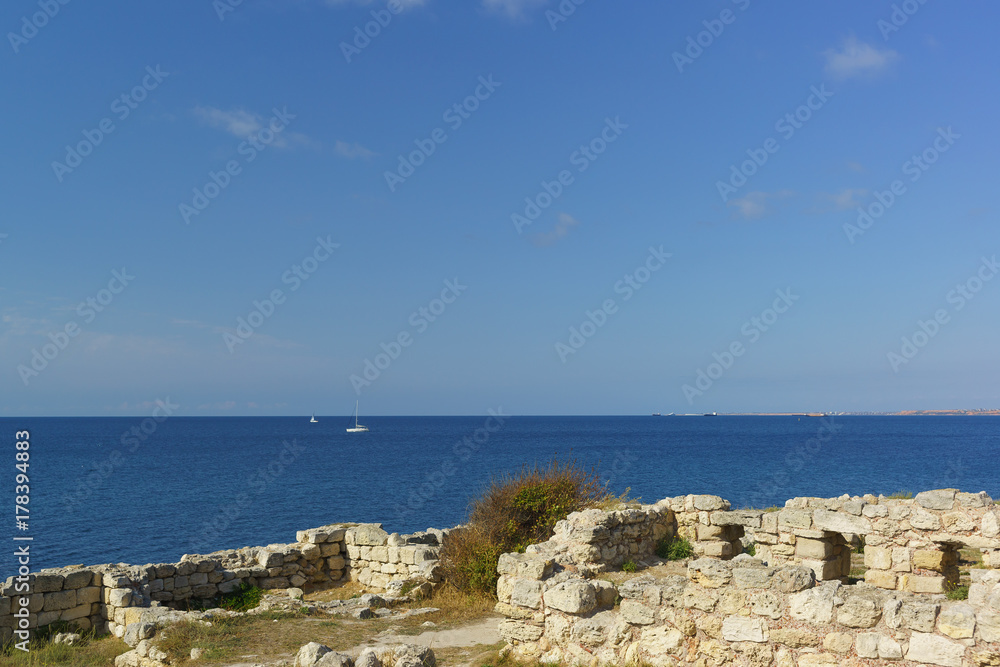Ruins of ancient buildings on the shore of the Black sea with blue water
