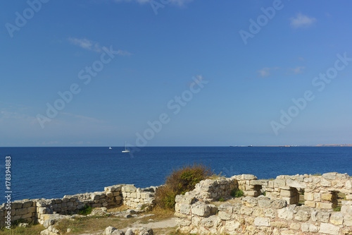 Ruins of ancient buildings on the shore of the Black sea with blue water