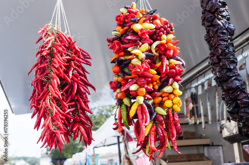 Hanging strands of mixed colorful chili peppers for sale at Sineu market, Majorca, Spain photo