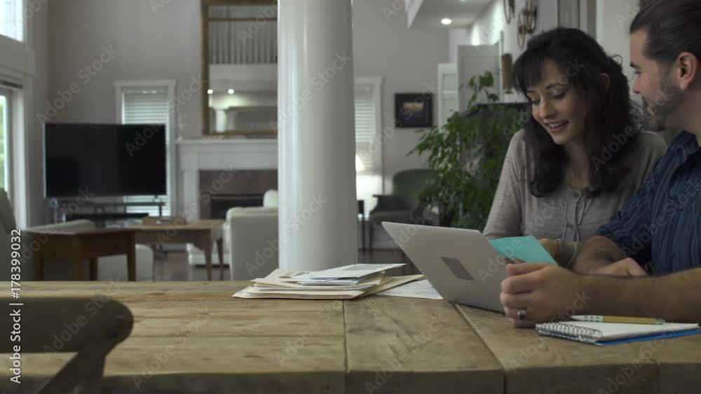 Dolly shot of a couple using a laptop in a dining room Dolly shot of a couple using a laptop in a dining room