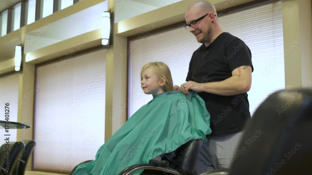 Hairdresser putting a cape on a girl Hairdresser putting a cape on a girl