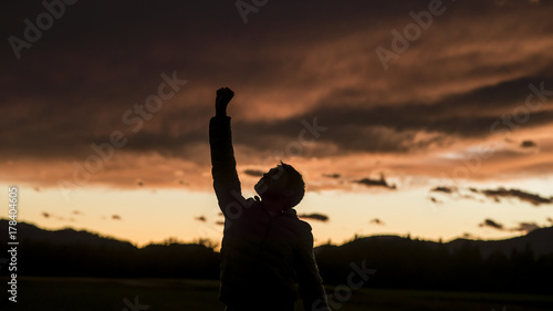 Man raising his fist against sunset sky photo