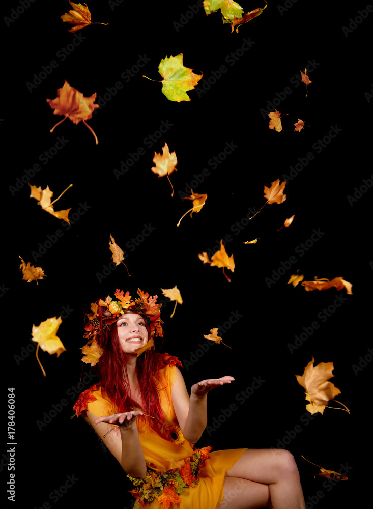 A beautiful young woman dresses up as an Autumn fairy and wears a wreath on her head made out of Autumn leaves. She poses for the camera while Autumn leaves fly around her. A beautiful young woman dresses up as an Autumn fairy and wears a wreath on her head made out of Autumn leaves. She poses for the camera while Autumn leaves fly around her.