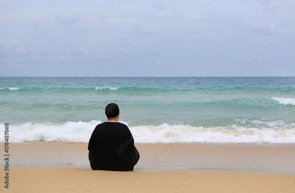 Back view Lonely woman in black dress sitting on the beach.