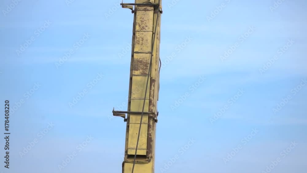 Slow motion shoting of a building crane against a blue sky background