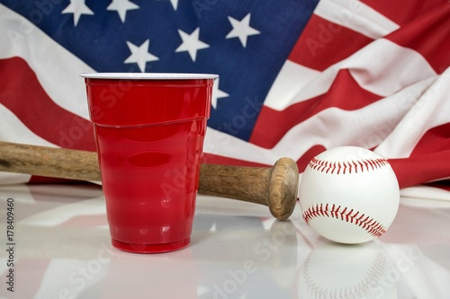 wooden bat and baseball with red party cup and American flag background