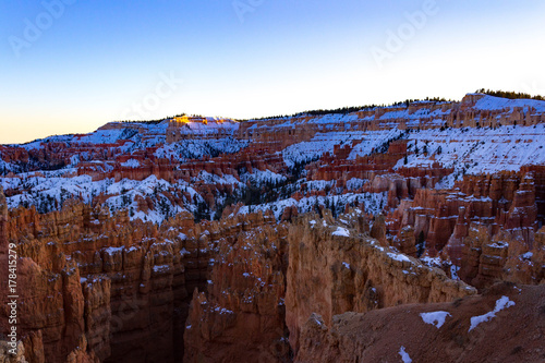 Beautiful Bryce Canyon in Utah with a blanket of snow during sunset.