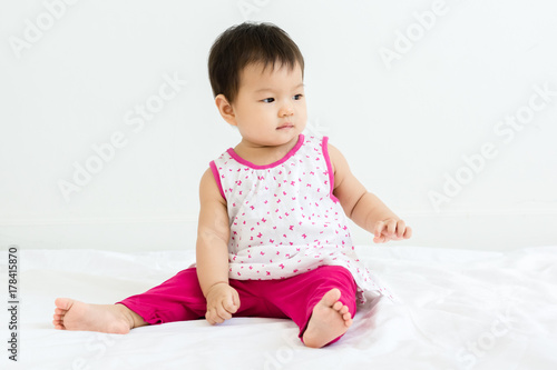 Portrait of adorable baby girl sitting on the bed