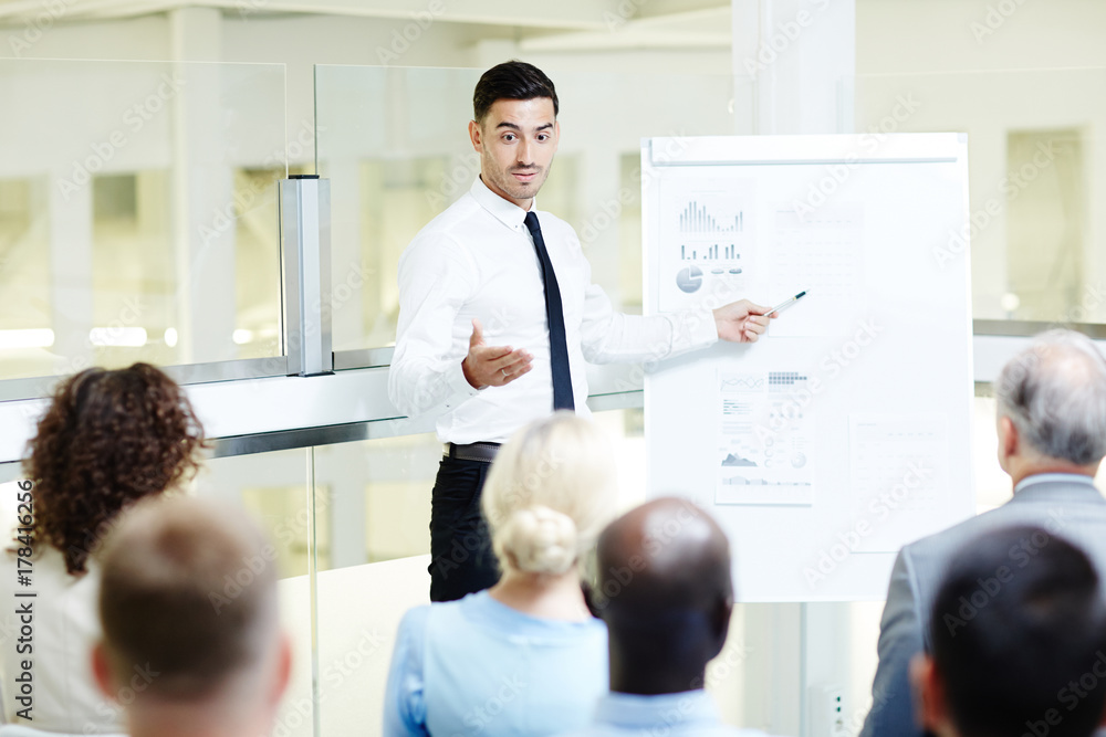 Young coach pointing at data on whiteboard during presentation of his plan