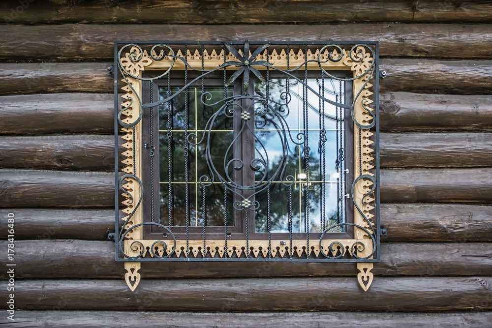 Window with decorative bars on the wooden wall