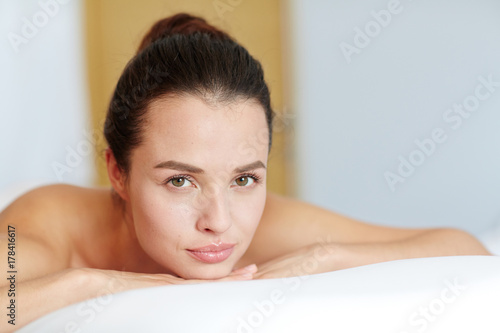 Relaxed young female with natural makeup looking at camera in spa salon